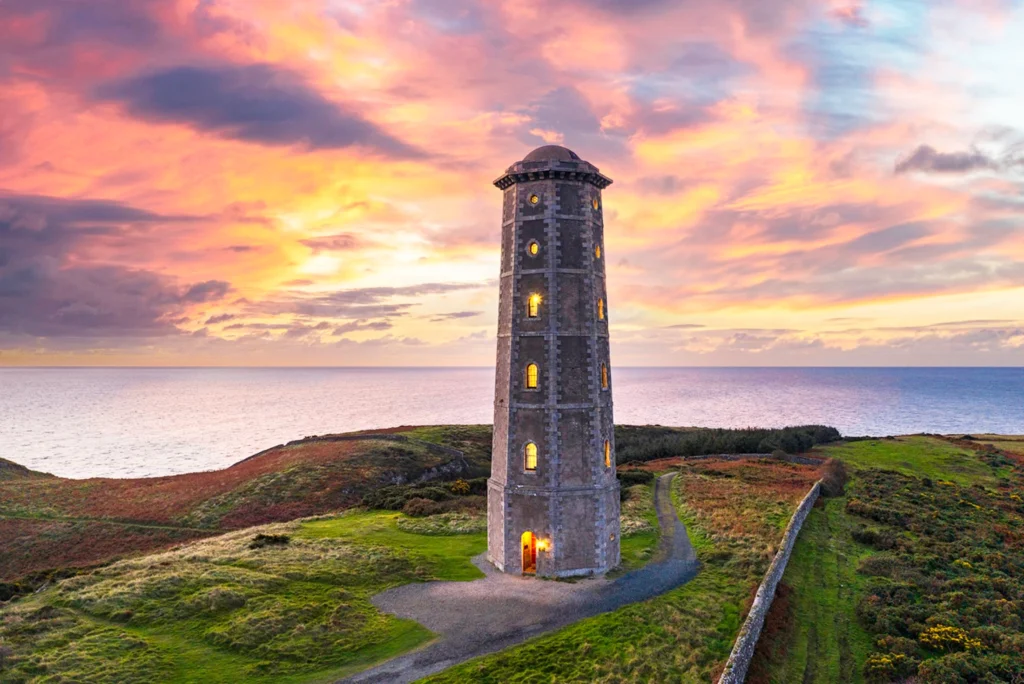 Wicklow Head Lighthouse glowing at sunrise above the Irish Sea